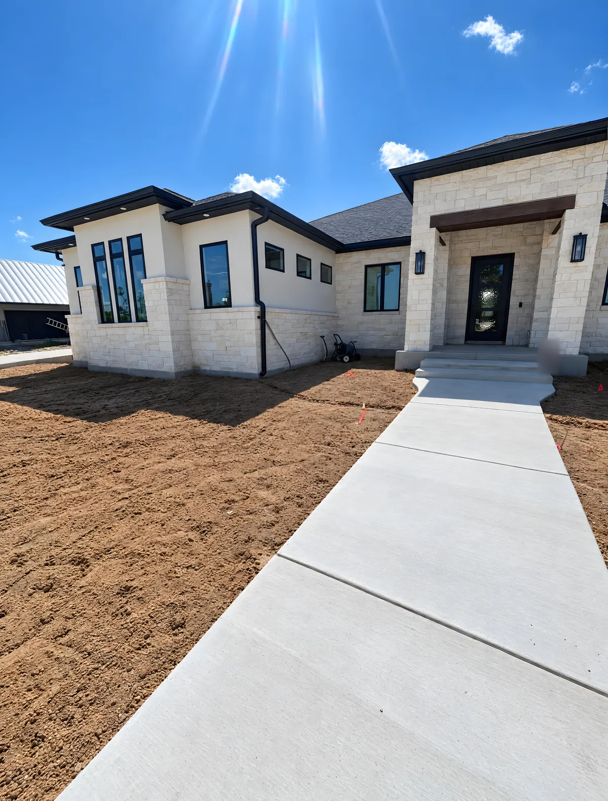 A new white stone house with dark bronze gutters and downspouts