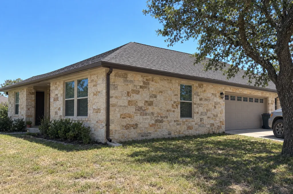 A one-storey limestone home with bronze seamless gutters along the eave and a downspout at the corner